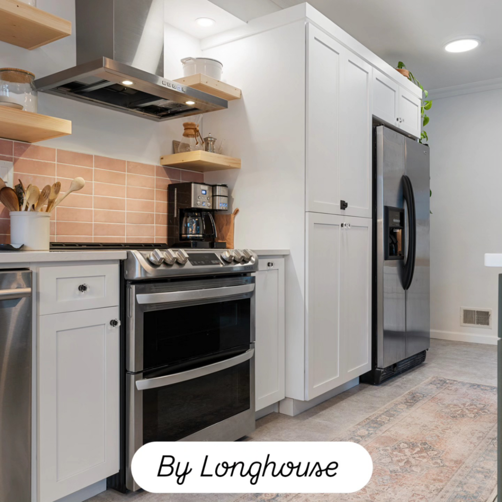A modern kitchen with new white cabinets, stainless steel appliances, and a range hood by Longhouse Construction Inc. in Estacada, OR.
