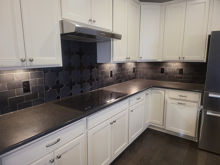 Modern kitchen renovation with white cabinets and a dark patterned backsplash by APS Residential Services in Livonia, MI.