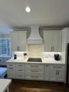 A newly installed modern kitchen with white cabinets, range hood, and subway tile backsplash by Branch Home Improvement LLC in Raleigh, NC.