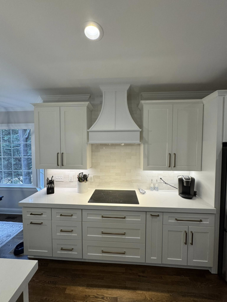 A newly installed modern kitchen with white cabinets, range hood, and subway tile backsplash by Branch Home Improvement LLC in Raleigh, NC.