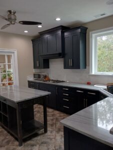 A modern kitchen featuring dark blue cabinets, white countertops, and stainless steel appliances by Coastal Surface Design in Virginia Beach, VA.