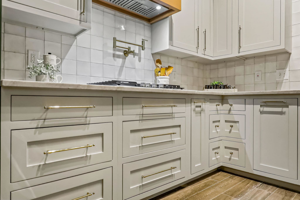 Modern light gray kitchen cabinets with gold hardware and a marble-look countertop by Innovative Design & Construction in Linwood, KS.