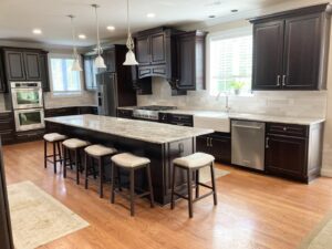 A spacious modern kitchen with dark wood cabinets, a large island, and new appliances installed by RW Contracting Phila, LLC in Philadelphia, PA.