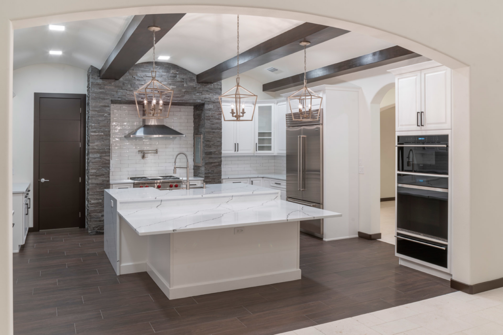 A modern kitchen design with white cabinets, a large island, and exposed beams by Cornerstone Custom Construction LLC in Beaver Falls, PA