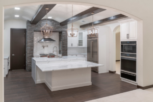 A modern kitchen design with white cabinets, a large island, and exposed beams by Cornerstone Custom Construction LLC in Beaver Falls, PA