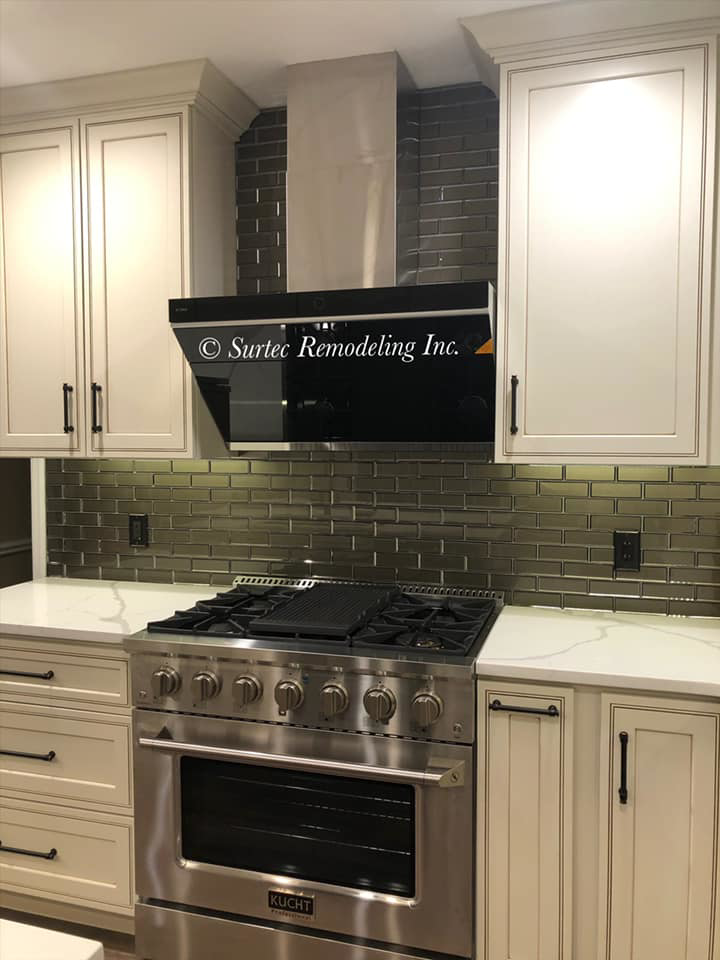 Modern kitchen design with white cabinets, dark tile backsplash, and stainless steel range by Surtec Remodeling Inc. in Pittsburgh, PA.