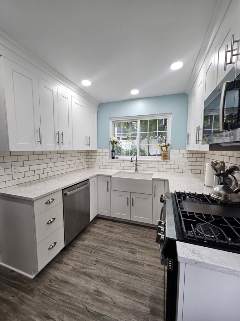 A modern kitchen featuring white cabinets, subway tile backsplash, and a farmhouse sink by Creative Building & Remodeling in Warren, MI