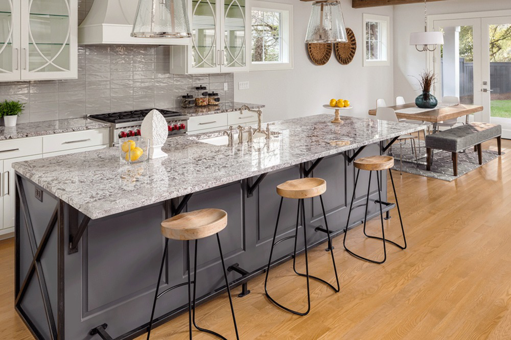 A modern kitchen featuring granite island countertops and bar stools by L&M Granite Countertops in Phoenix, AZ.