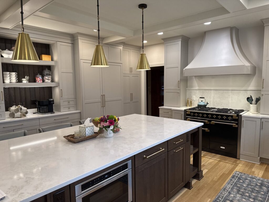 A modern kitchen remodel featuring light grey cabinets, a large island, and gold pendant lights by Saunders Dynamic Remodeling in Columbus, OH