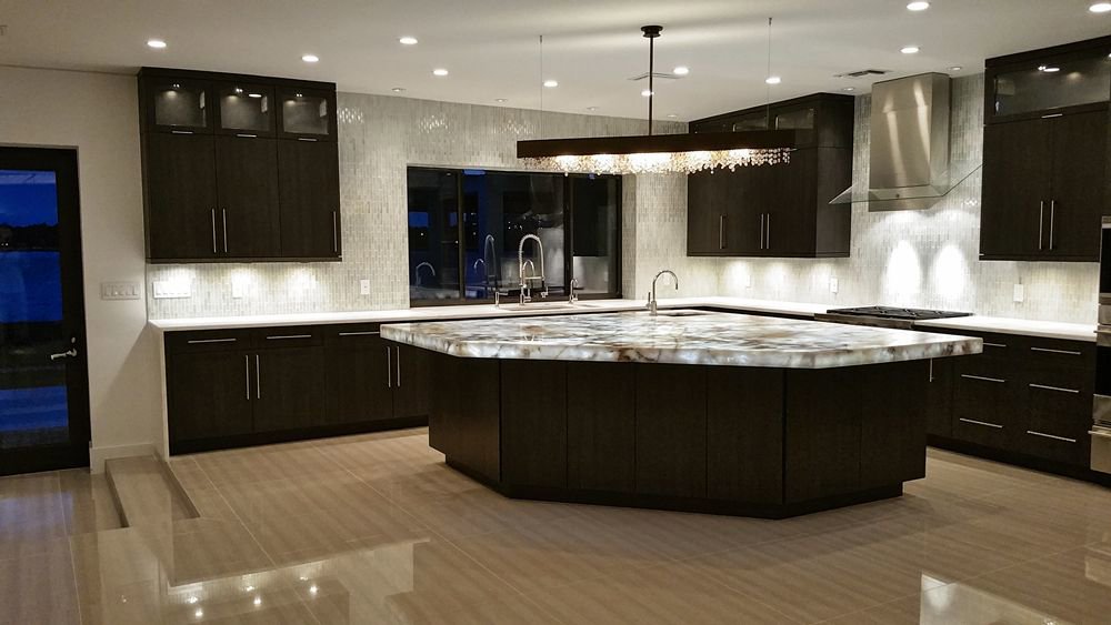 Modern kitchen with dark cabinets and a unique hexagonal island by Charter Bay Home Builders in Tampa, FL