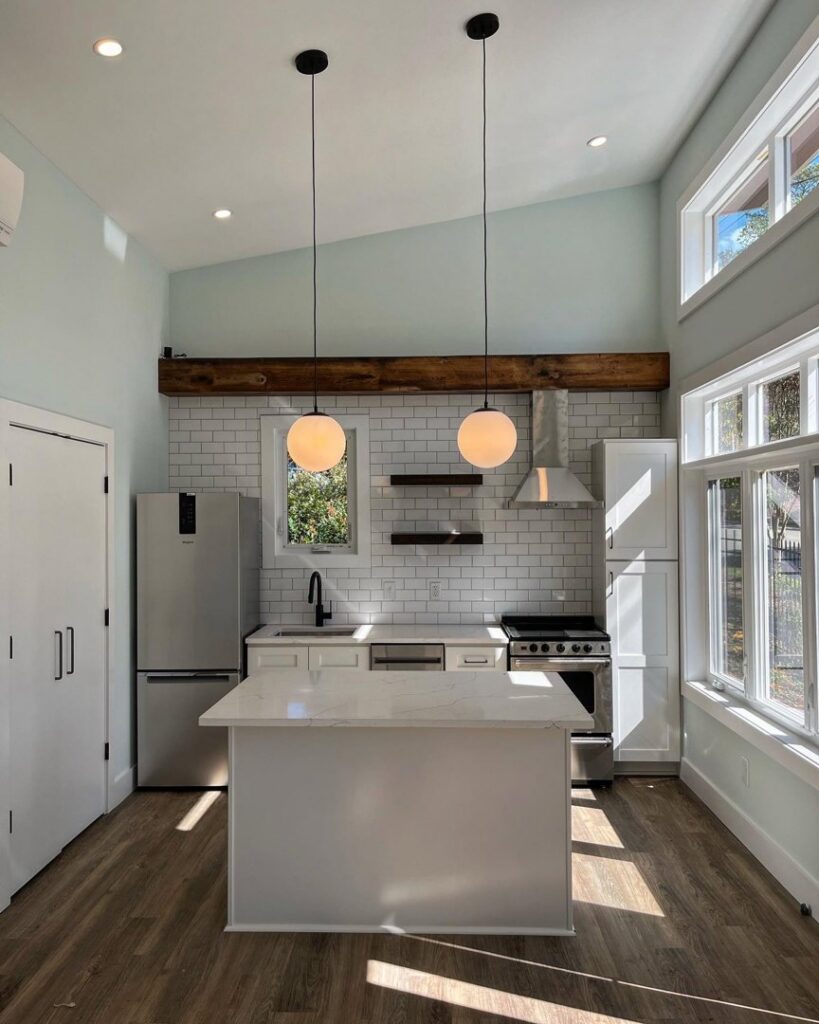 A modern kitchen installation with white cabinets, subway tile backsplash, and pendant lighting by Falls Contracting, LLC in Raleigh, NC.