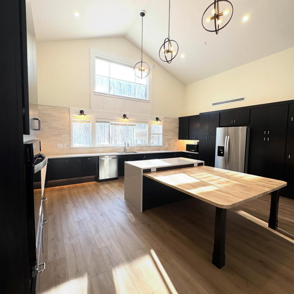 A beautifully installed modern kitchen with black cabinets and a large island by Mason Sky Enterprises in Worcester, MA.
