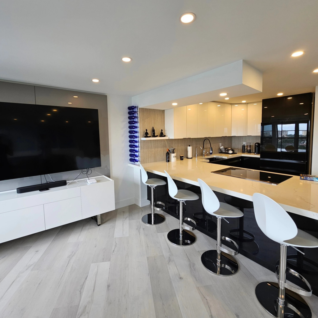 A modern open-plan kitchen and living area with sleek cabinetry and a large island, completed by JNY Remodeling INC in Fort Lauderdale, FL.