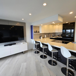 A modern open-plan kitchen and living area with sleek cabinetry and a large island, completed by JNY Remodeling INC in Fort Lauderdale, FL.