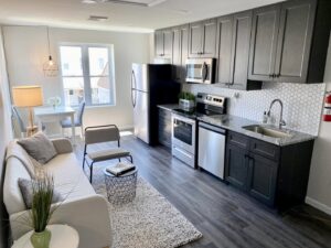 A modern kitchen and living room renovation featuring new flooring, cabinets, and a tiled backsplash by Tile Jawn in Philadelphia, PA.