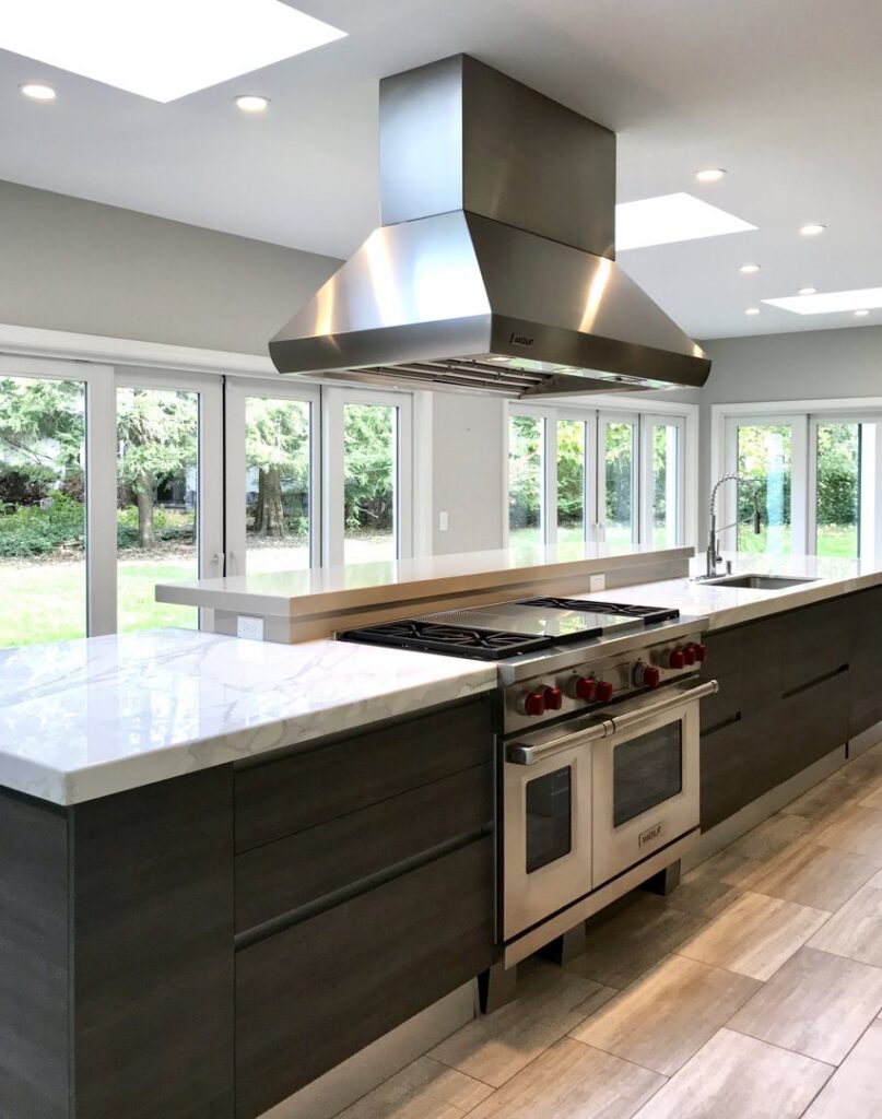 A modern kitchen featuring a large stainless steel range hood and island, built by Creasey Construction of Illinois, Inc. in Springfield, IL