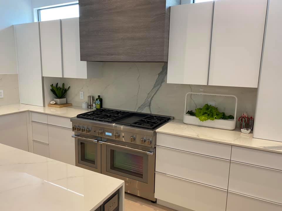 A modern kitchen with new white cabinets, a large range, and marble backsplash installed by Dahlman Construction in San Tan Valley, AZ.