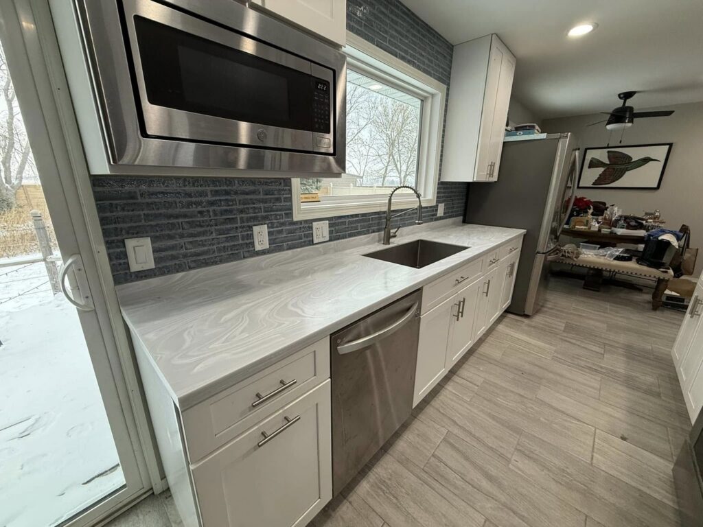 A modern kitchen remodel featuring new countertops, sink, microwave, and backsplash by Watertown Handyman in Watertown, SD.