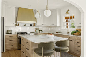 A modern kitchen remodel featuring light wood cabinets, a marble island, and a brass range hood, by Northrup Remodeling in Minneapolis, MN