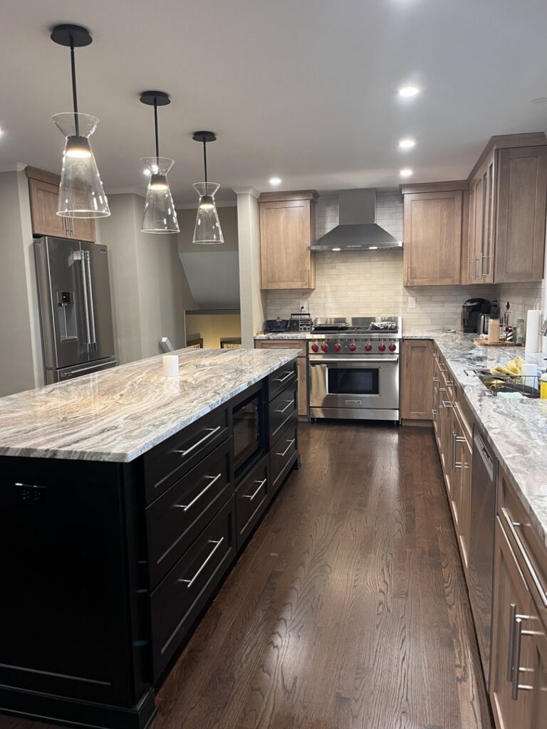 Stunning modern kitchen remodel featuring wood cabinets, a large island with marble countertop, and stainless steel appliances by Byrd's Contracting, LLC in Bristol, CT.