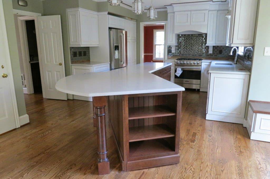 A modern kitchen remodel featuring white cabinets, hardwood floors, and a unique curved island by Rice Building Company in Rocky Mount, NC.
