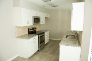 A newly remodeled modern kitchen featuring white cabinets, granite countertops, stainless steel appliances, and a tiled backsplash by Custer Remodeling in Plano, TX.