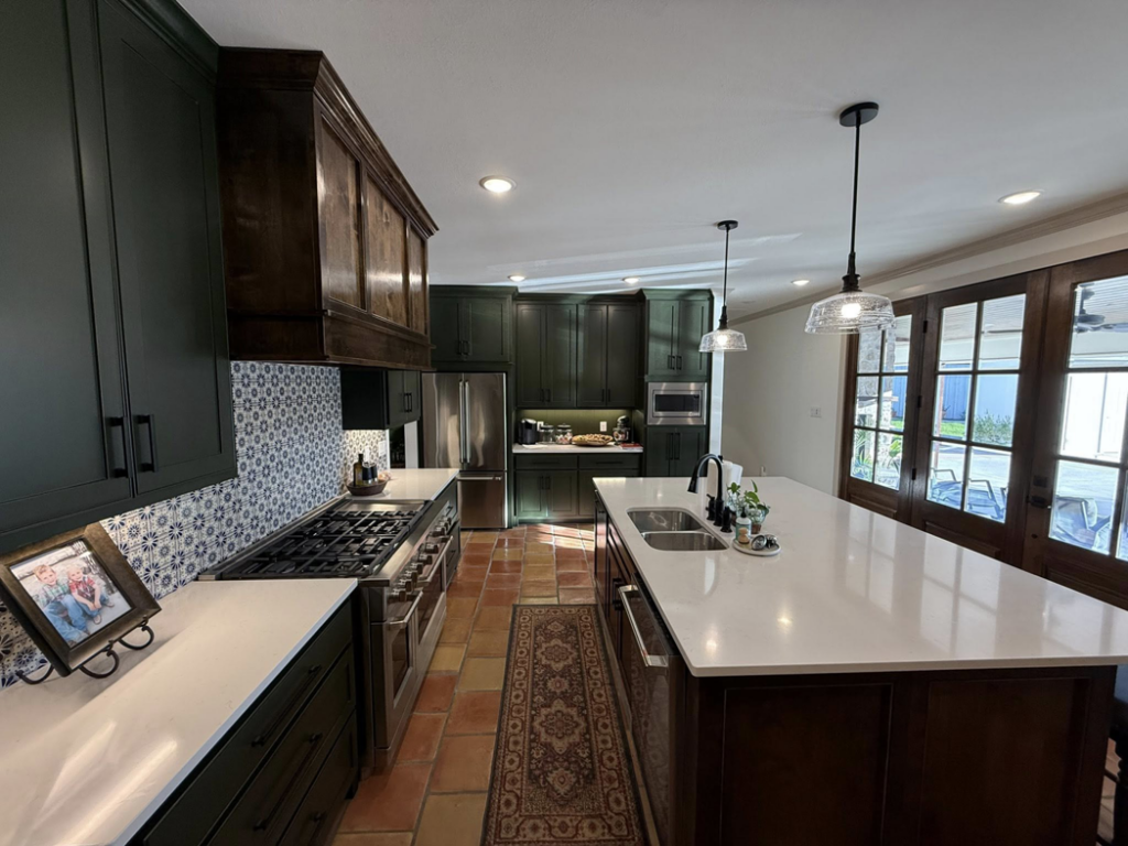 A modern kitchen remodel featuring dark green cabinets, white countertops, a decorative tiled backsplash, and a large island, completed by Javier's Painting in San Angelo, TX.