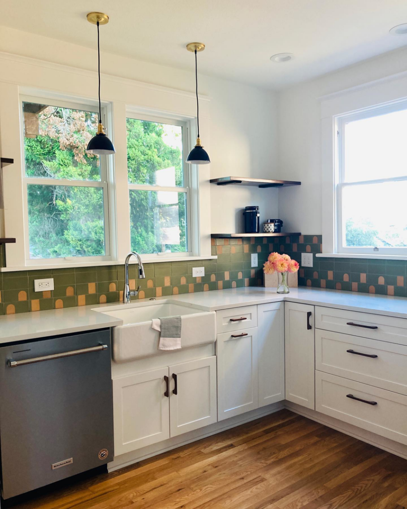 A modern kitchen remodel featuring white cabinets, a farmhouse sink, and tile backsplash by Nation / Phillips Construction in Tacoma, WA.