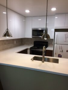 A modern kitchen remodel featuring white cabinets and pendant lighting by Kennyman The Handyman Inc. in San Francisco, CA