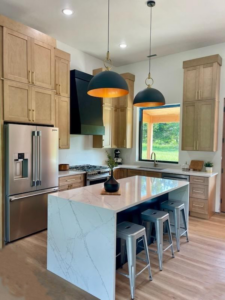 A beautifully remodeled modern kitchen with light wood cabinets and a large island by Slater Cabinets and More in Springfield, MO.