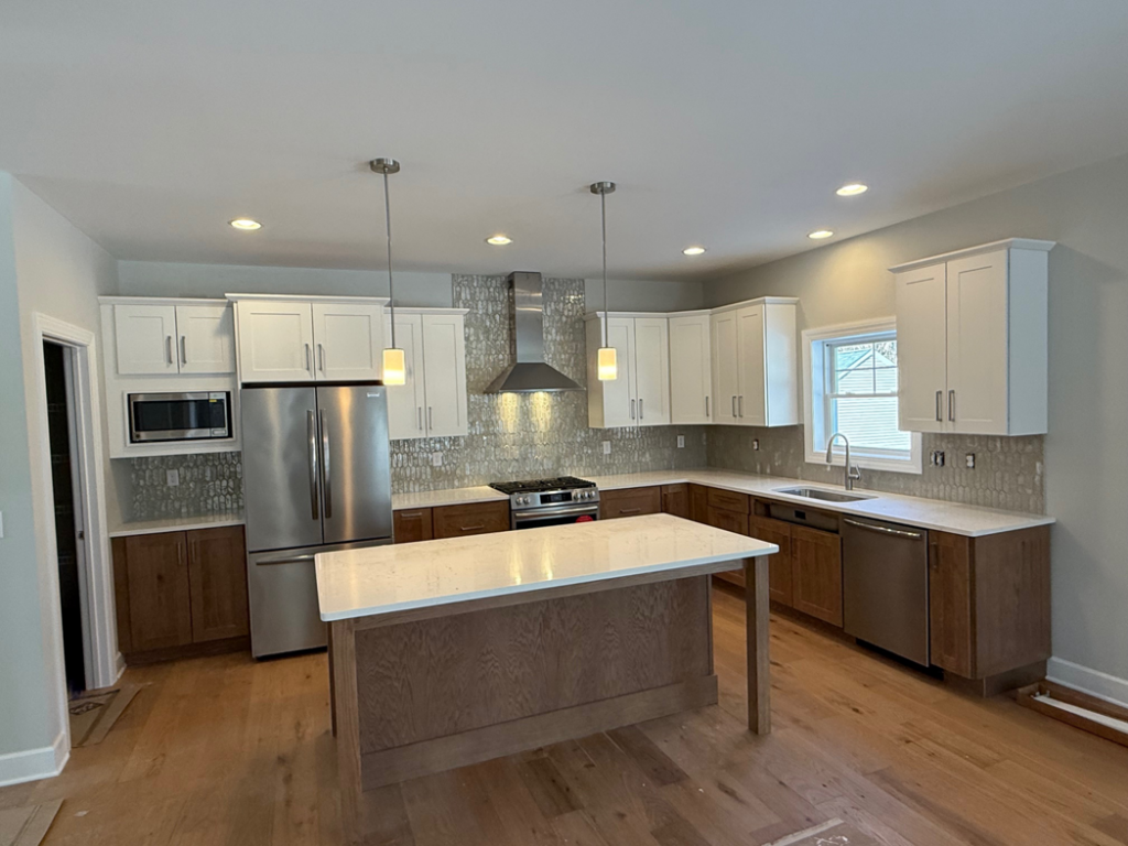A modern kitchen remodel featuring two-tone cabinets and a large island completed by McDonald Custom Homes in Schenectady, NY.