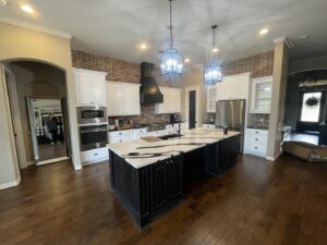 A modern kitchen remodel featuring new white cabinets, a large island, and brick backsplash by R and R contractors in Rogers, AR.