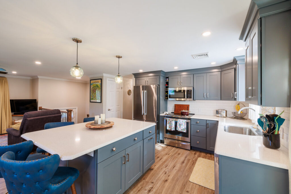 A modern kitchen remodel featuring blue-grey cabinets, a large island, and stainless steel appliances by Pluff Contractors LLC in Lancaster, PA.