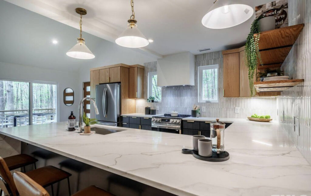 A modern kitchen remodel showcasing two-tone wood and dark cabinets, a large island, and a stylish tiled backsplash by Pro Finishes NC, LLC in Raleigh, NC.