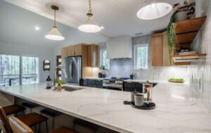 A modern kitchen remodel showcasing two-tone wood and dark cabinets, a large island, and a stylish tiled backsplash by Pro Finishes NC, LLC in Raleigh, NC.