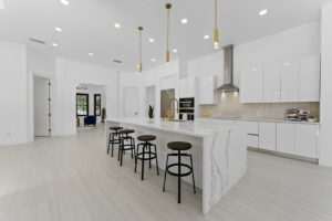 A newly completed modern kitchen remodel with white cabinets and gold fixtures by Beyond Builders in Tampa, FL