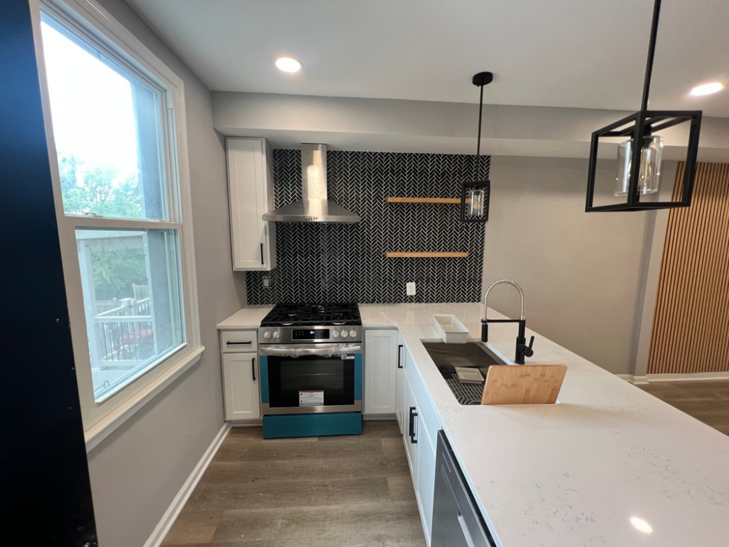 A modern kitchen remodel featuring a black herringbone tile backsplash, white cabinets, and new appliances by Home Style Improvement in Frederick, MD.