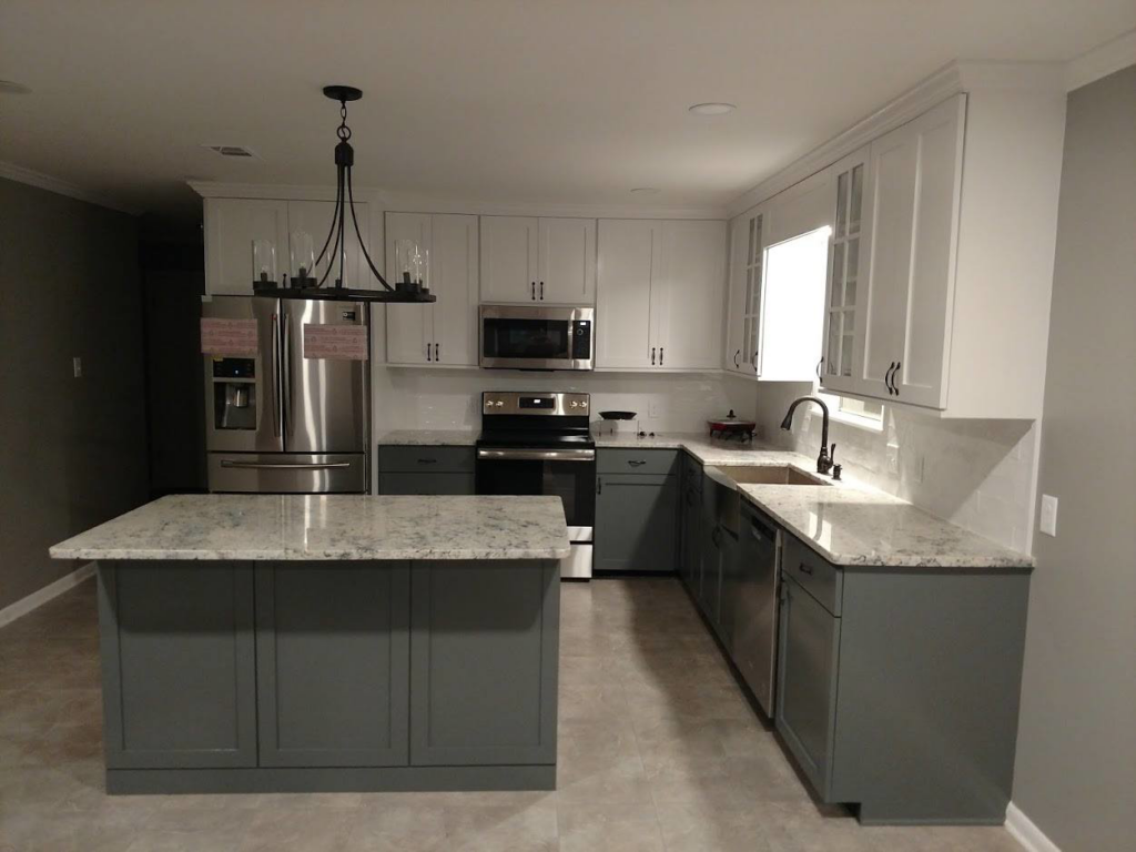 A modern kitchen remodel featuring a gray island, white and gray cabinets, and stainless steel appliances by Rex Austin's Remodeling in Ball, LA.