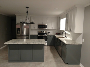 A modern kitchen remodel featuring a gray island, white and gray cabinets, and stainless steel appliances by Rex Austin's Remodeling in Ball, LA.