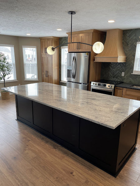 A modern kitchen remodel featuring a large island with granite countertops by Benjamin Design - Build in Fishers, IN.