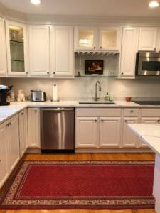 A completed modern kitchen renovation with white cabinets and stainless steel appliances by Camelot Builders in Essex, CT.