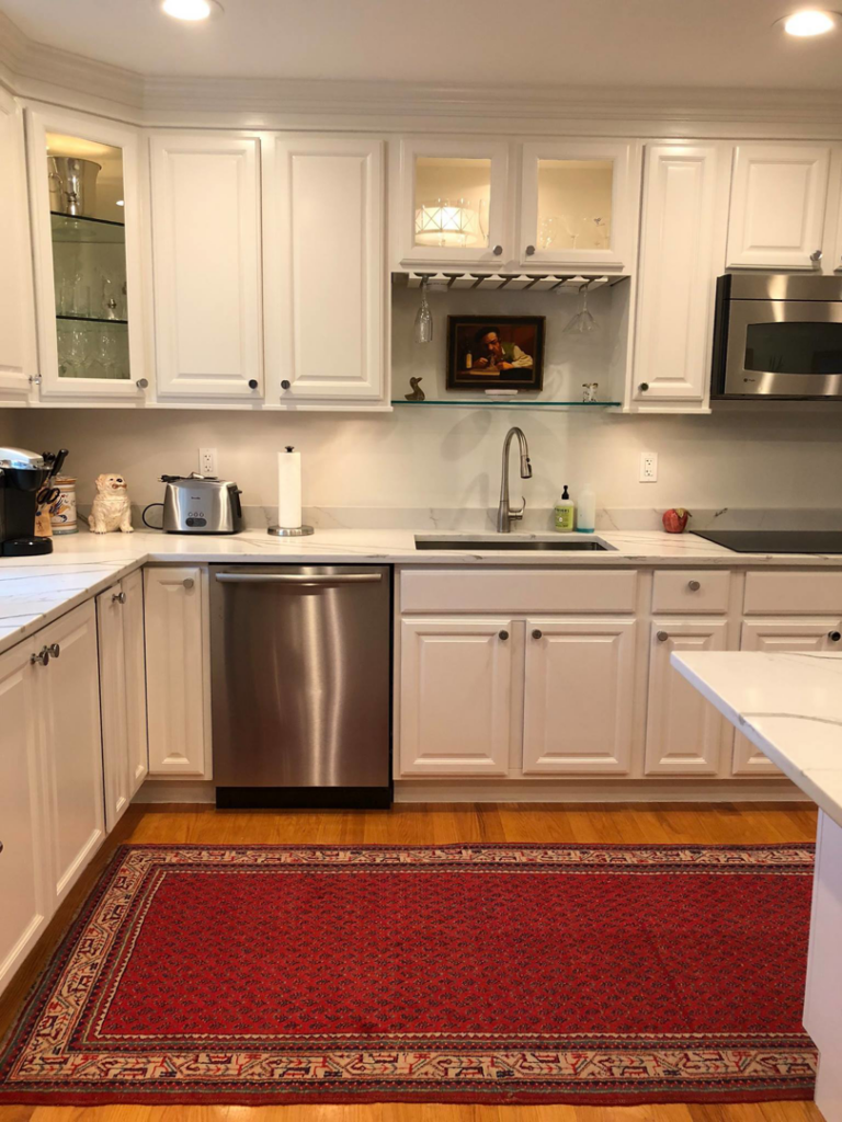 A completed modern kitchen renovation with white cabinets and stainless steel appliances by Camelot Builders in Essex, CT.