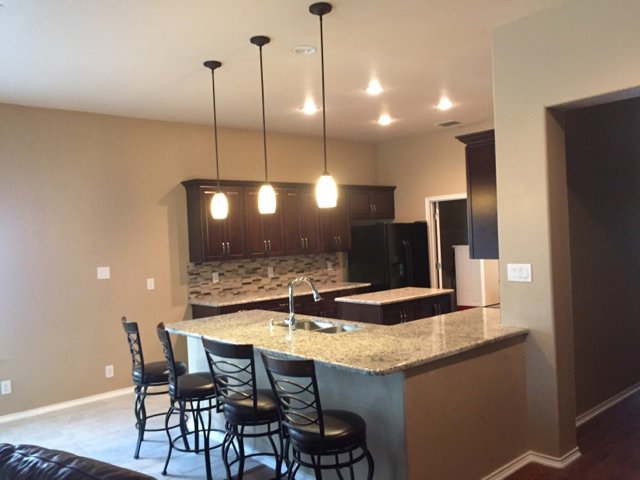A newly renovated modern kitchen with granite countertops and dark cabinets completed by PaRu Construction LLC in San Antonio, TX