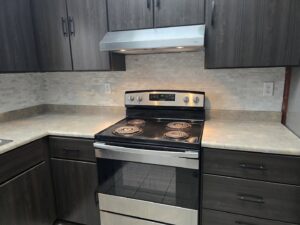 A modern kitchen renovation showcasing dark cabinets, a tiled backsplash, and a new stove by Ben Nye The Fix-It Guy in Erie, PA.