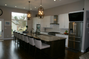 A modern kitchen renovation featuring white cabinets, a dark island, and stainless steel appliances by Davinci Cabinets & Design in St. Louis, MO.