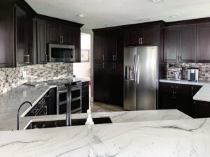 A modern kitchen renovation featuring dark cabinets and stainless steel appliances by Florida Palm Construction, Inc. in Davie, FL
