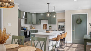 A modern kitchen renovation with green cabinets, a large island, and dining area by Garrett Group Construction in Philadelphia, PA.