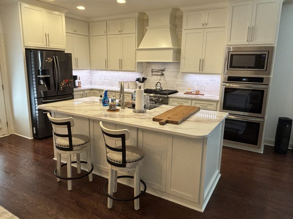 A modern kitchen renovation featuring a large island, white cabinets, and stainless steel appliances by Cannon & Associates in Montgomery, AL.