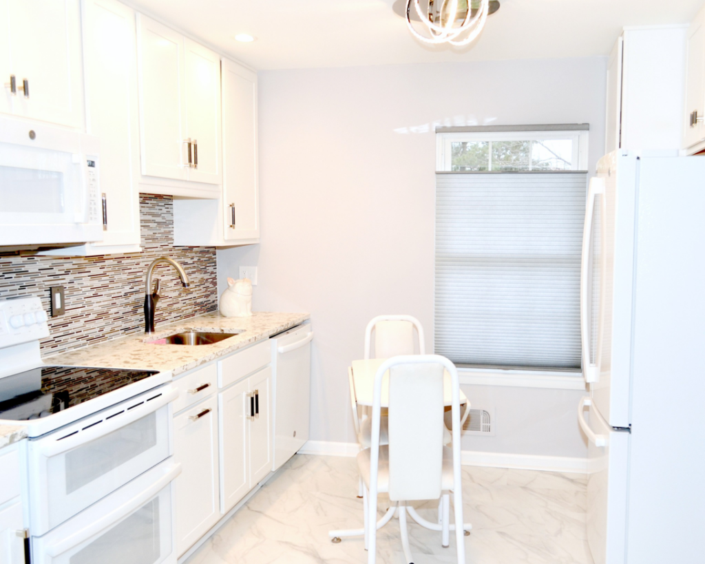 A newly renovated modern kitchen with white cabinets and stainless steel appliances by Patriot Construction in Rochester, NY