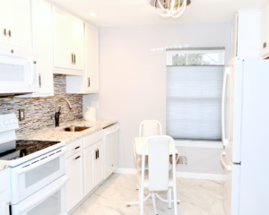 A newly renovated modern kitchen with white cabinets and stainless steel appliances by Patriot Construction in Rochester, NY